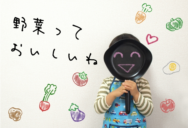 野菜のイラストと笑顔が描かれたフライパンを持つ子供